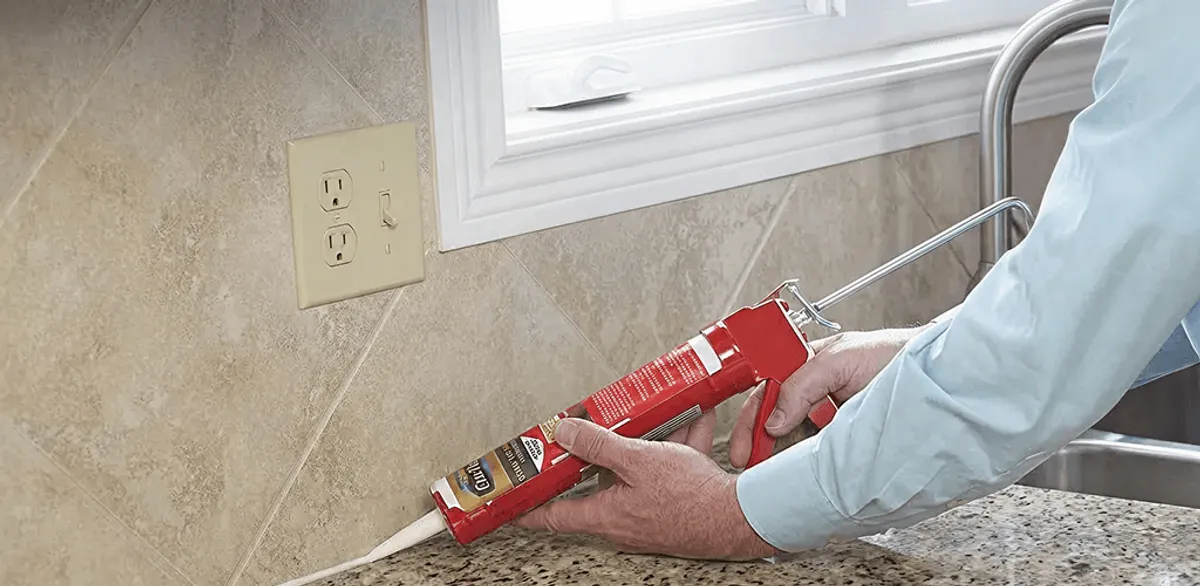 Handyman applying caulk along a kitchen backsplash and countertop seam in Charlotte, NC