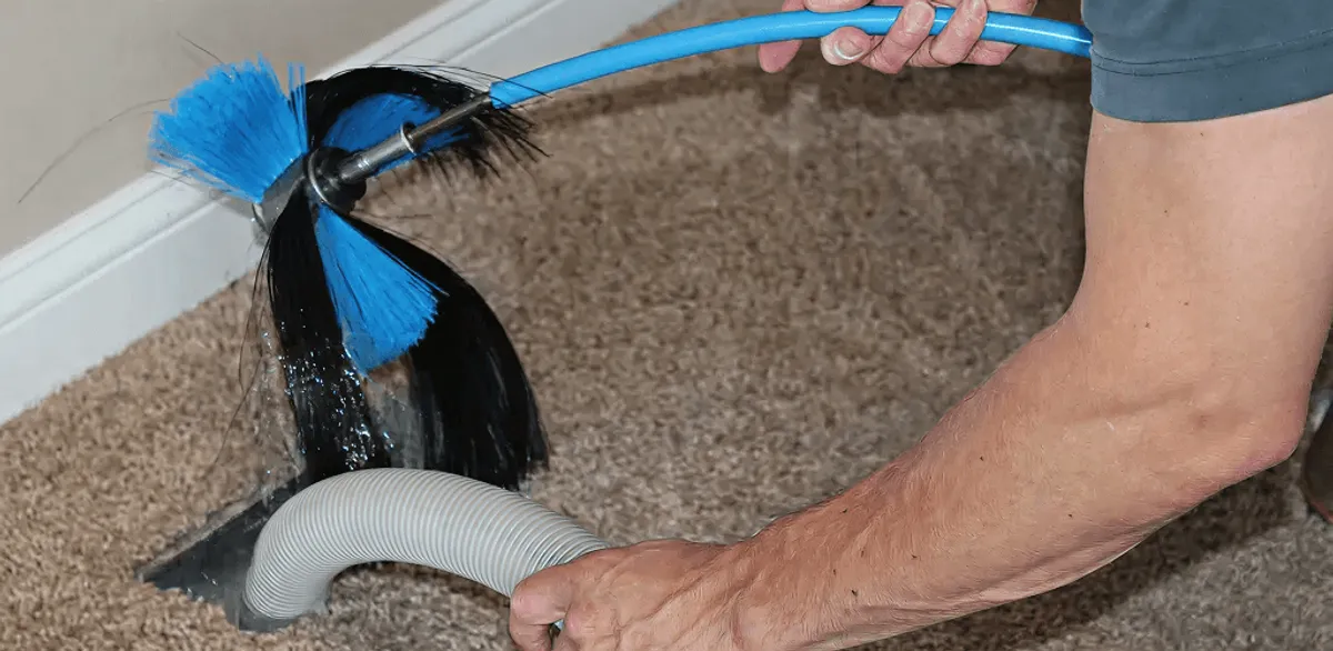 Dryer vent cleaning technician brushing lint from a vent line in Charlotte, NC