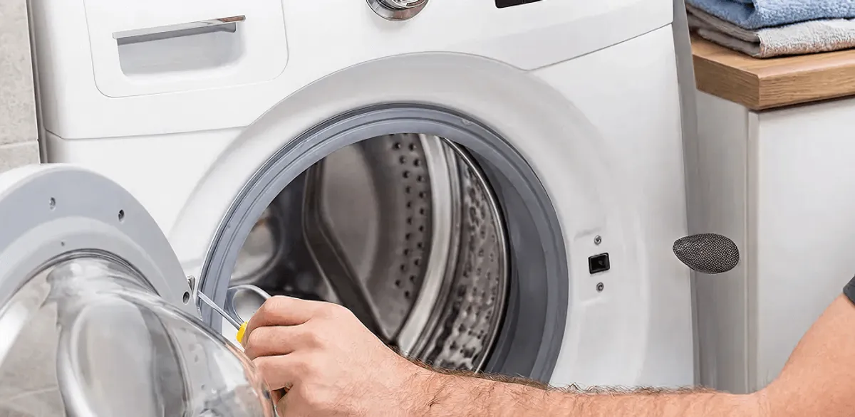 Handyman repairing a front-load washing machine and inspecting the drum in Charlotte, NC