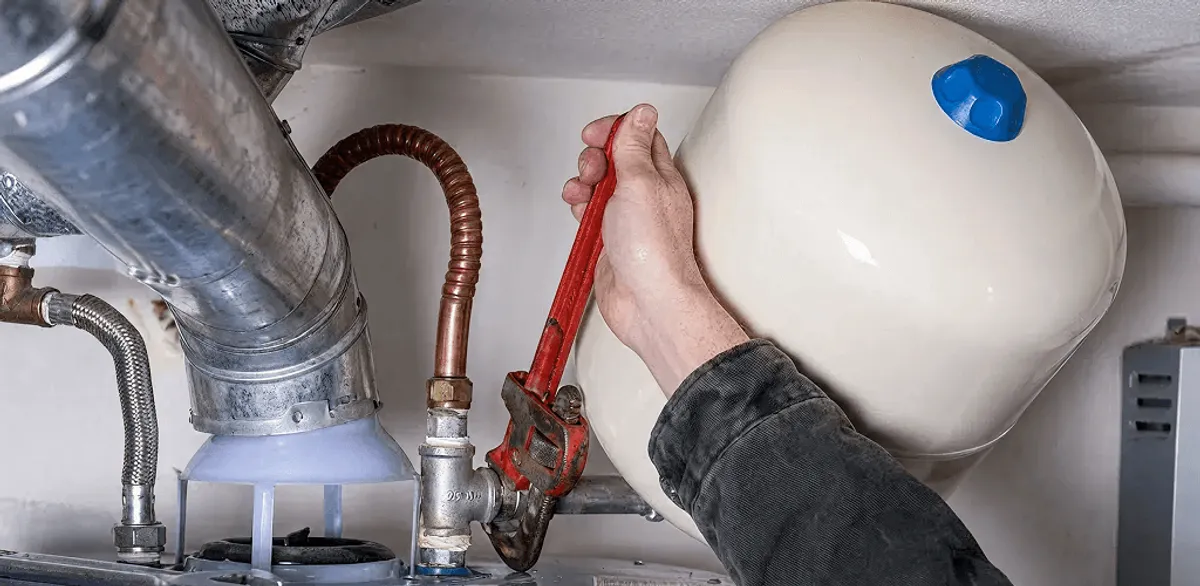 Water heater repair technician tightening plumbing connections near a tank unit in Charlotte, NC